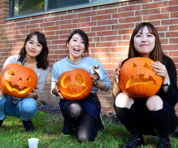 three young women with carved pumpkins