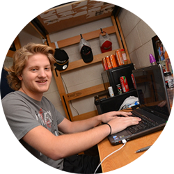 a young man with a laptop in a dorm room