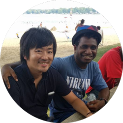 two young men sit near a lake