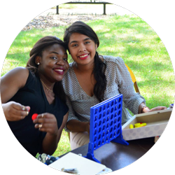 two young woman sit at a table outdoors